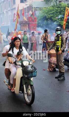 Phuket Town / Thailand - 7. Oktober 2019: Phuket Vegetarian Festival oder Nine Emperor Gods Festival Parade mit Frau und Kind auf dem Motorrad, Polizist Stockfoto