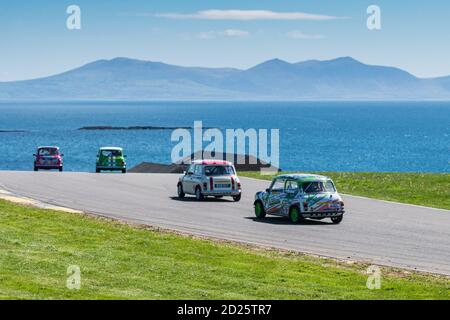 Mächtige Minis Rennen auf Anglesey Circuit mit Snowdonia und die Menai Strait als Hintergrund Stockfoto