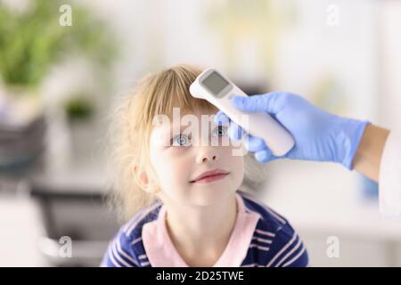 Kinderarzt Arzt in Gummihandschuh misst Temperatur des Kindes mit Infrarot-Thermometer Porträt Stockfoto