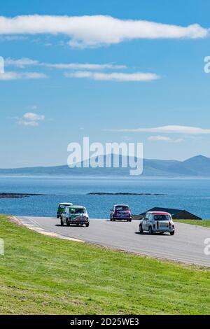 Mächtige Minis Rennen auf Anglesey Circuit mit Snowdonia und die Menai Strait als Hintergrund Stockfoto