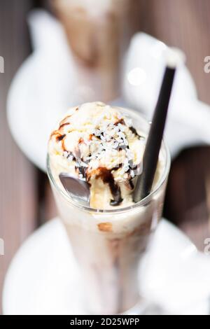 Nahaufnahme von Eiskaffee auf einem Holztisch mit Sahne in sie gegossen zeigt die Textur und erfrischenden Blick des Getränks. Stockfoto