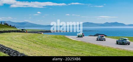 Mächtige Minis Rennen auf Anglesey Circuit mit Snowdonia und die Menai Strait als Hintergrund Stockfoto