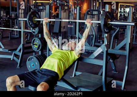 Übungen mit schwerem Gewicht. Die Grenzen des menschlichen Körpers zu überschreiten. Starker reifer Kaukasianer, der im Fitnessstudio eine gewichtete Bar oder Langhantel hebt Stockfoto