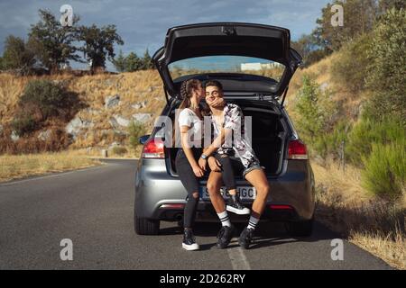 Pärchen sitzt im Kofferraum, während sie auf den Abschleppwagen wartet Um anzukommen Stockfoto