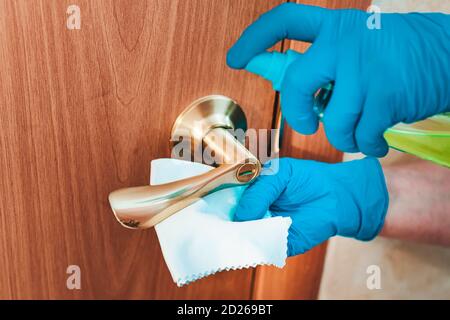 Dekontamination des Türgriffs aus Metall. Entfernen von Keimen aus dem Griff an der vorderen Klappe. Sprühen Sie mit einem Desinfektionsmittel und einem Lappen in der Hand einer Frau. Der Stockfoto