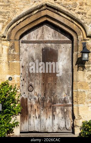 Eine alte, mittelalterliche Holztür am Eingang zu einem traditionellen Cotswold Cottage House, Burford, Gloucestershire, England, Großbritannien Stockfoto