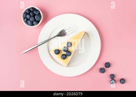 Käsekuchen mit Heidelbeeren auf rosa Hintergrund, Draufsicht. Ein Stück Käsekuchen Stockfoto
