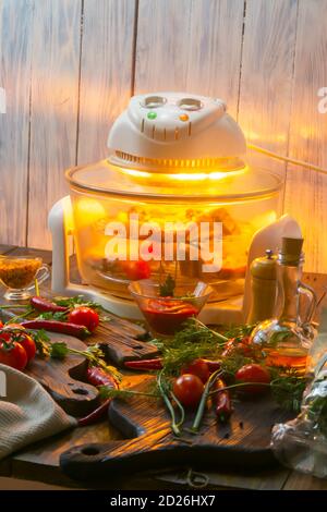 Gegrilltes Fleisch im Aero Grill auf einem Holztisch gegrillt. In der Nähe Gemüse und Gewürze auf alten Schneidebrettern. Selektiver Fokus, Nahaufnahme. Stockfoto