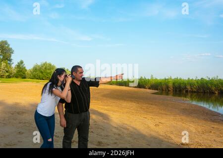 Ein Vater lehrt seine kleine Tochter zu fotografieren. Am Ufer des Sees lernen Fotografen das Fotografieren. Stockfoto