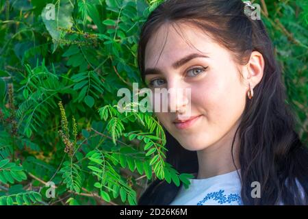 Junge schöne Frau schaut auf die Kamera und lächelt. Schönes Bokeh, selektiver Fokus. Brünette Frau Porträt. Frohe Sommerzeit. Stockfoto