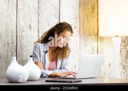 Seriöse junge professionelle Frau, die von zu Hause aus auf einem Laptop arbeitet Computer während der Covid-19 Pandemie in einem Remote-Arbeit oder Telearbeitkonzept Stockfoto