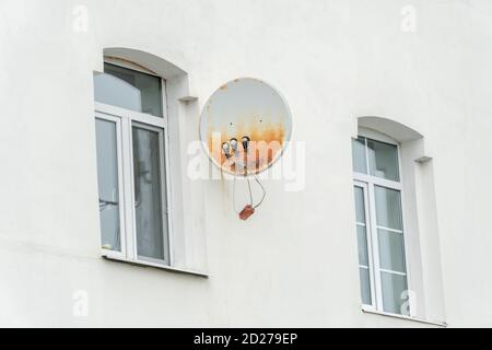 Rostige Satellitenschüssel an der weißen Wand des Hauses Mit Fenstern aus der Nähe Stockfoto