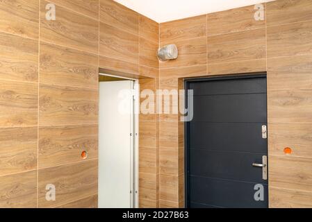 Moderner Gaskessel-Raum mit braunen Keramikfliesen, die Holz imitieren, leerer Raum ohne Installation, sichtbare Eingangstür zum Heizraum. Stockfoto