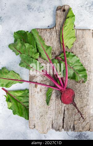 Frische Rote Bete mit Blättern auf einem Holzbrett. Gesunde Ernährung. Rote Bete. Bio-Rübe, Rote Bete auf grauem rustikalem Hintergrund. Grünes Wohnkonzept. Organisch Stockfoto