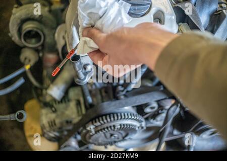 Ein Automechaniker überprüft den Ölstand in einem Automotor während der Routinewartung. Nahaufnahme Stockfoto