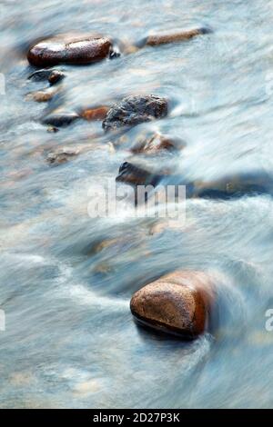 Wasser fließt über Felsen in einem kleinen Bach. Stockfoto