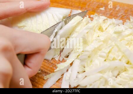 Damenhände mit einem Messer schneiden Peking Kohl hellgrün. Gemüsesalat kochen, Seitenansicht Stockfoto