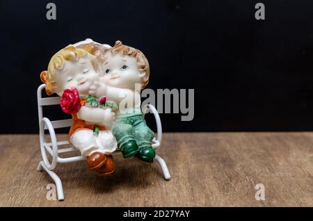 Die keramischen Figuren der Kinder auf der Bank auf hölzern Hintergrund Stockfoto