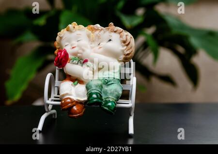 Keramische Figuren von Kindern auf einer Bank auf einem schwarzen Hintergrund Stockfoto