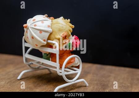 Keramikfiguren von Kindern mit einem Regenschirm auf einer Bank Mit dem Rücken zur Kamera auf einem Holzhintergrund Stockfoto