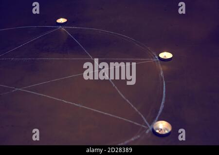 Kerzen auf einem Pentagramm auf dem Holzboden. Magisches Ritual mit okkulten, bösen und esoterischen Symbolen. Schrecklicher Ritus von Halloween Stockfoto