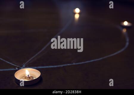 Kerzen auf einem Pentagramm auf dem Holzboden. Magisches Ritual mit okkulten, bösen und esoterischen Symbolen. Schrecklicher Ritus von Halloween Stockfoto