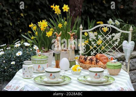 ostertisch Dekoration mit Tee Porzellan und Croissants im Frühjahr Garten Stockfoto