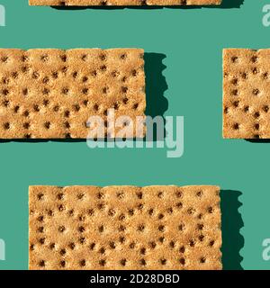 Foto in Form eines nahtlosen Musters. Orangefarbene Loafs für gesunde Lebensmittel mit Schatten auf einem grünen Hintergrund. Stockfoto