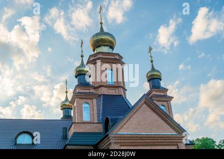 Teil der orthodoxen Kirche mit vier Kuppeln und Kreuzen aus der Nähe gegen den blauen Himmel. Orthodoxes Kreuz Stockfoto