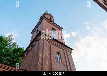 Teil einer Backsteinkirche mit einer Kuppel und einem Kreuz Nahaufnahme gegen einen blauen Himmel. Orthodoxes Kreuz. Foto von unten nach oben Stockfoto