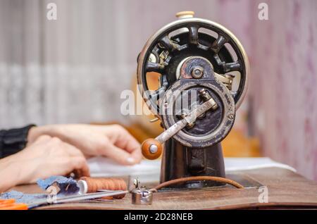 Frau, die an einer alten Nähmaschine arbeitet. Nahaufnahme der Hände Stockfoto