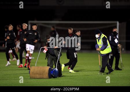 Bodenpersonal benutzt eine Rolle und eine Pitchgabel auf dem Platz vor dem EFL Trophy Spiel im PTS Academy Stadium, Northampton. Stockfoto