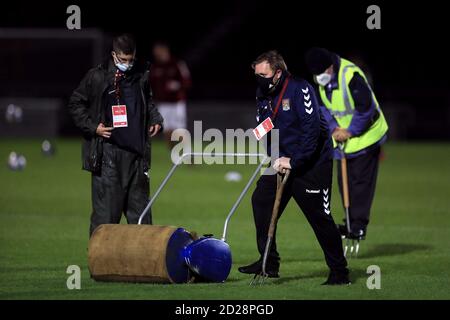 Bodenpersonal benutzt eine Rolle und eine Pitchgabel auf dem Platz vor dem EFL Trophy Spiel im PTS Academy Stadium, Northampton. Stockfoto