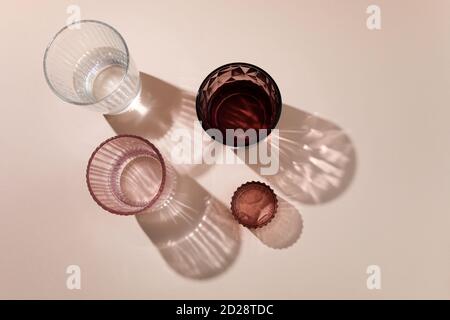 Sparcling Brille mit langen harten Schatten auf biege Hintergrund. Sommerstill Life Konzept Stockfoto