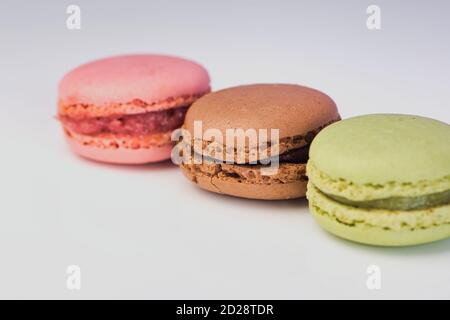Makrofoto von grünen, roten und braunen Macarons von der Seite vor weißem Hintergrund Stockfoto