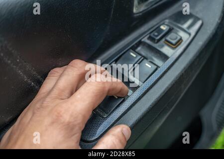 Die Hand eines Mannes drückt die Taste für die Türverriegelung des Autos Verriegeln und entriegeln Sie die Autotür aus der Nahaufnahme von innen Stockfoto