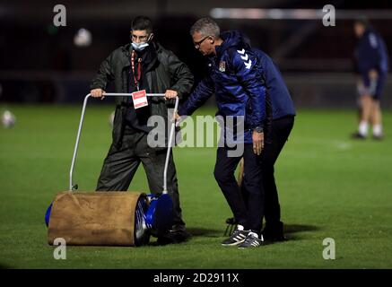 Northampton Stadtmanager Keith Curle hilft dem Bodenpersonal mit einem Roller, wie sie auf dem Platz vor dem EFL Trophy Spiel im PTS Academy Stadium, Northampton neigen. Stockfoto