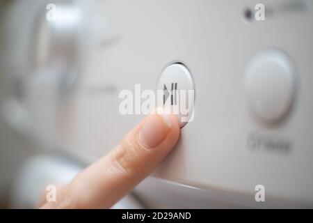 Mädchen Hand drückt die Start, Pause-Taste auf dem Bedienfeld der Waschmaschine Nahaufnahme Stockfoto