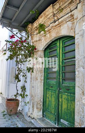 Eine schöne zypriotische antike olivgrüne Tür in Girne. Die Farbe der Tür ist abgesplittert und verwittert gegen die alte Steinfassade im griechischen Stil mit Dekoration Stockfoto