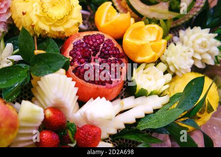 Granatapfel, Orange und Erdbeere in Form von schönen Blumen zur Tischdekoration, Schnitzerei mit Gemüse und Früchten Stockfoto