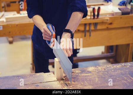 Zimmermann schneidet einen Holzblock mit einer Handsäge, Nahaufnahme Stockfoto