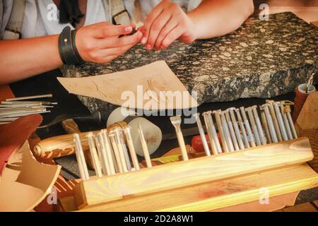 Hände des Meisters Verarbeitung und Ledergerbung. Retro Schuhmacher Werkzeuge, Nahaufnahme. Vintage-Toolkit für Gerberarbeiten. Stockfoto