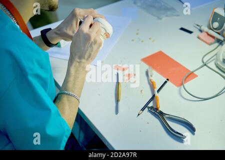 Zahnersatz in den Händen eines männlichen Zahnarztes. Der Prothetist arbeitet an der Schaffung eines falschen Kiefers. Stockfoto