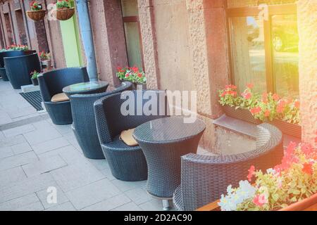 Sommercafé auf der Straße der Großstadt. Außenterrasse des Restaurants mit Rattantischen und Stühlen. Stockfoto