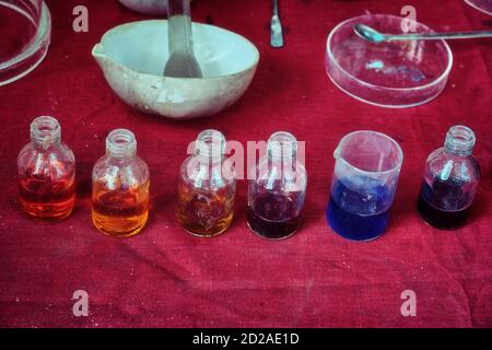 Gläser mit buntem Reagenz in einem alten chemischen Labor. Chemikalien in Flaschen mit farbigen Flüssigkeiten. Tabelle mit Werkzeugen und Matrizen für chemische Experimente Stockfoto