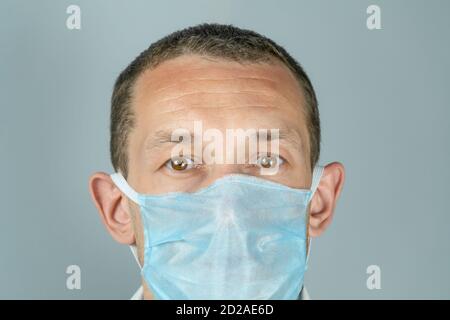 Nahaufnahme eines dunkelhaarigen Mannes mit braunen Augen Tragen einer medizinischen Maske Stockfoto