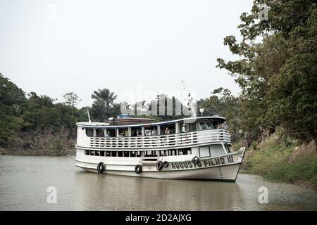 Amazon River in der Nähe von Santarem, Brasilien -- Dezember 02, 2015: weiße Kreuzfahrtschiff mit Touristen auf dem Deck schwimmend auf schmutzigen grünen Wasser des Flusses in der Nähe der Bäume an der Küste auf die natürlichen Hintergrund Stockfoto