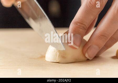 Frauenhände schneiden Pilze aus nächster Nähe auf einem Holzbrett Stockfoto