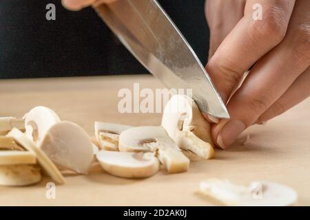 Frauenhände schneiden Pilze aus nächster Nähe auf einem Holzbrett Stockfoto