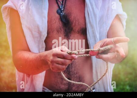 Wie man zwei Seile mit einem Seeknoten bindet. Ein junger Mann zeigt, wie man Knoten an einem Seil festbindet. Stockfoto